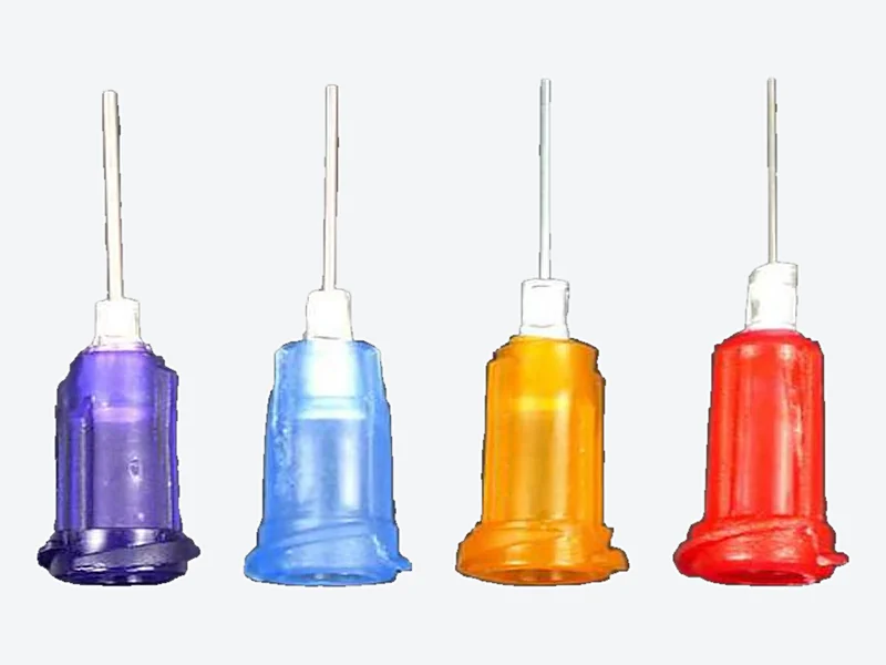 Four dispensing needles with purple, blue, orange and red plastic hubs and metal-reinforced tubes