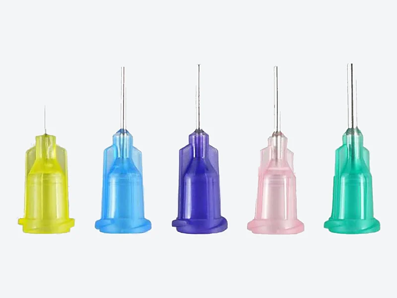 Five dispensing needles with yellow, blue, purple, pink and teal plastic hubs and thin metal tubes